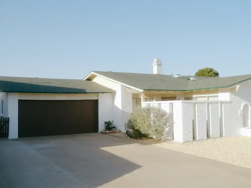 Single-story white ranch house with a two-car garage and a gravel yard